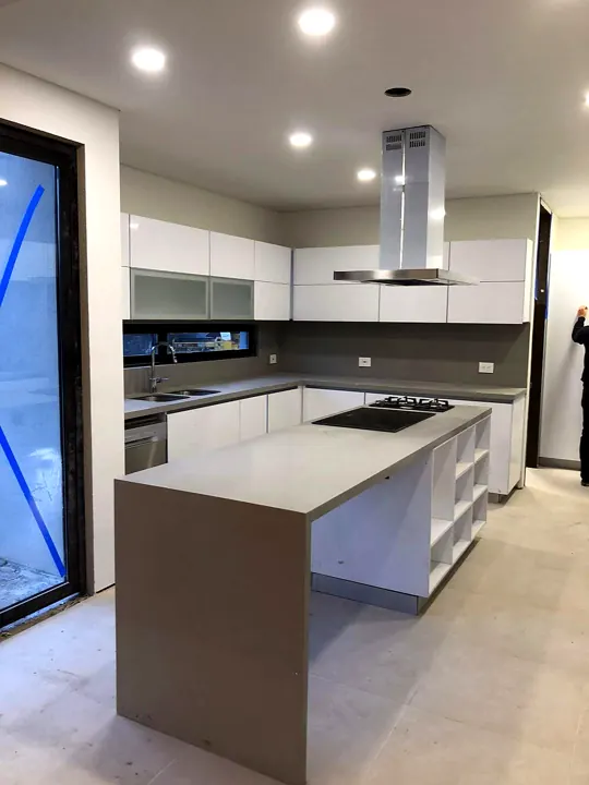 Cocina moderna con isla en cuarzo y gabinetes blancos en vivienda Steel Framing
