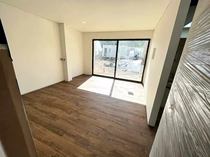 Habitación con piso laminado de madera y puerta-ventana corrediza